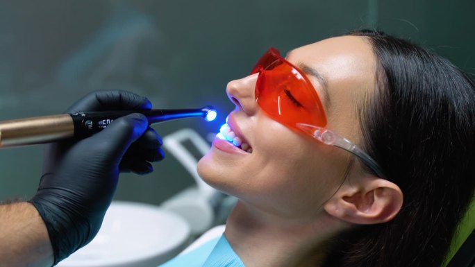 年轻女子在牙科诊所用紫外线烘干补牙