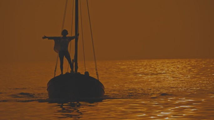 海岸奥德赛:女人站在船头伸出手臂，而男人熟练地引导船