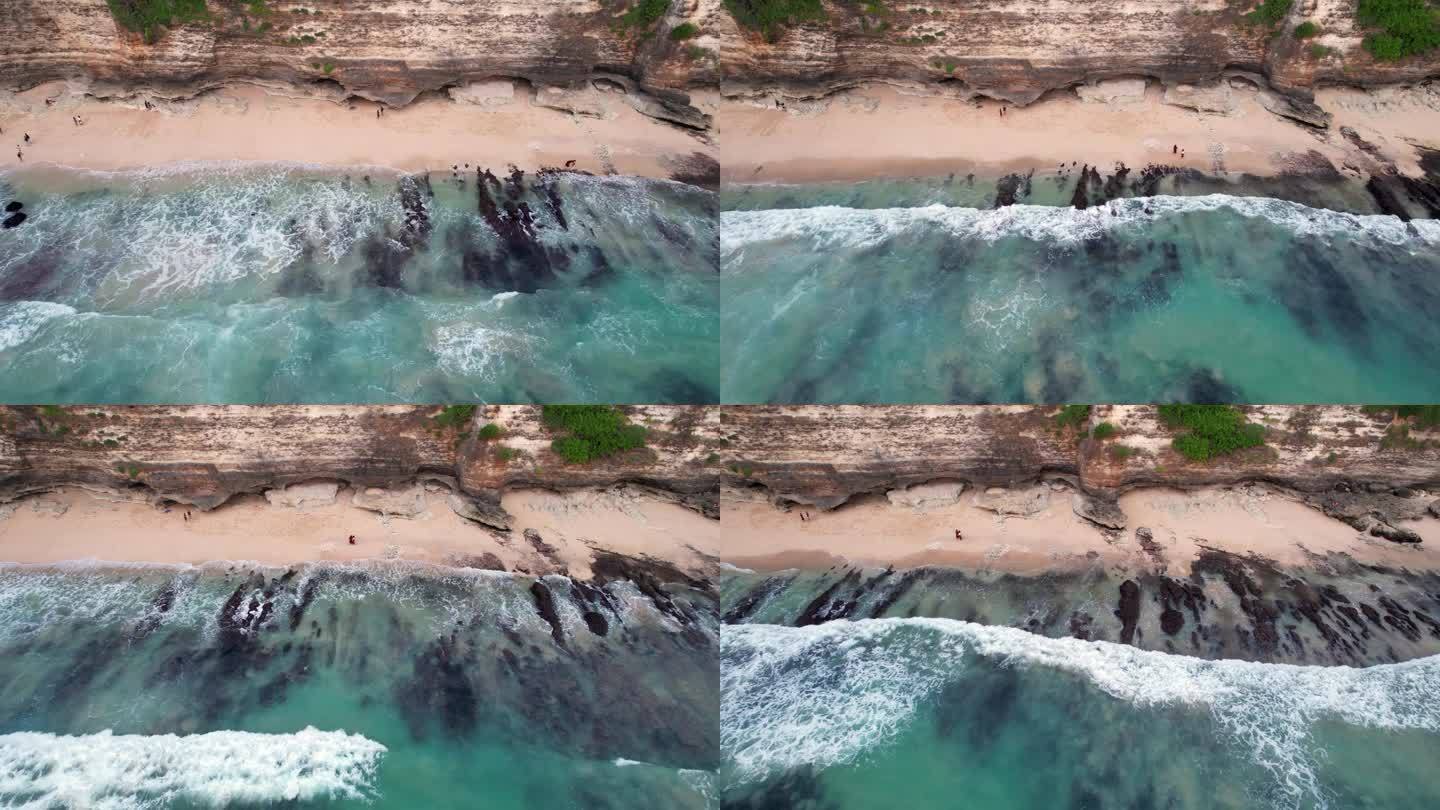 相当平静的海洋，小海浪冲刷着海滩，航拍相机沿着悬崖飞行