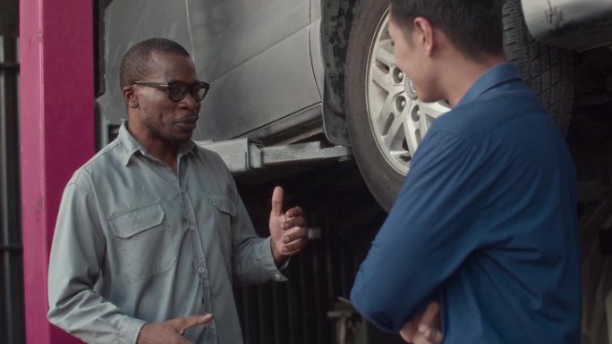 轮胎钳工向来访的汽车服务人员讲解车轮维修