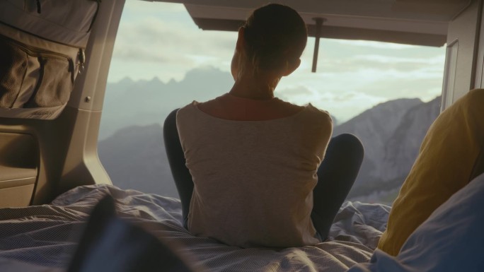 安静的女人在露营车里放松，享受山景。一个女人欣赏美丽的山景。