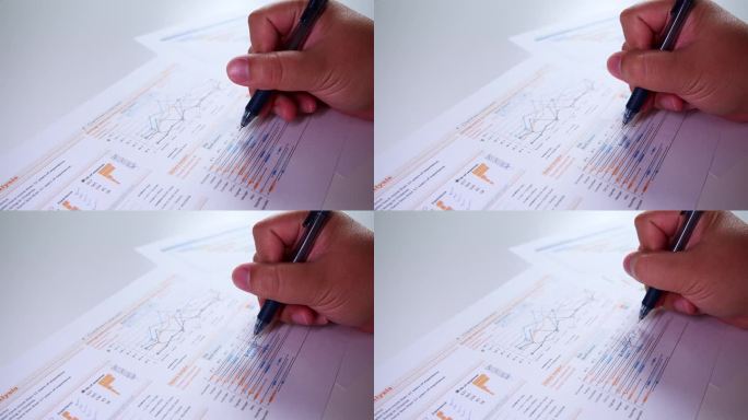 男人用手在纸上填笔。商人手拿笔在办公桌旁工作，分析仪表盘图形和图表，检查利润报告的特写。