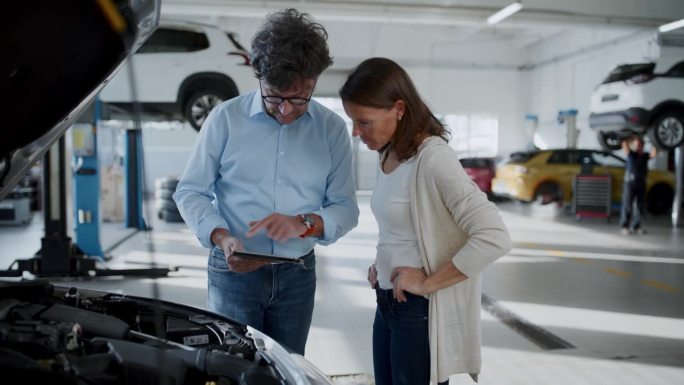 经理在维修车间向客户讲解汽车发动机的维修
