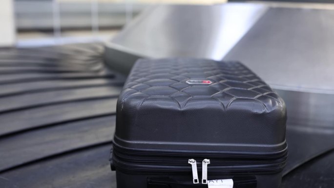一个手提箱放在机场到达大厅的行李传送带上