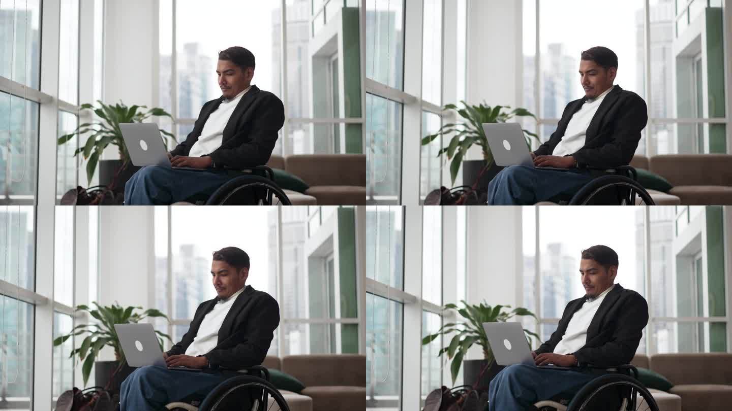 身体残疾的商人坐在轮椅上，在办公室使用笔记本电脑
