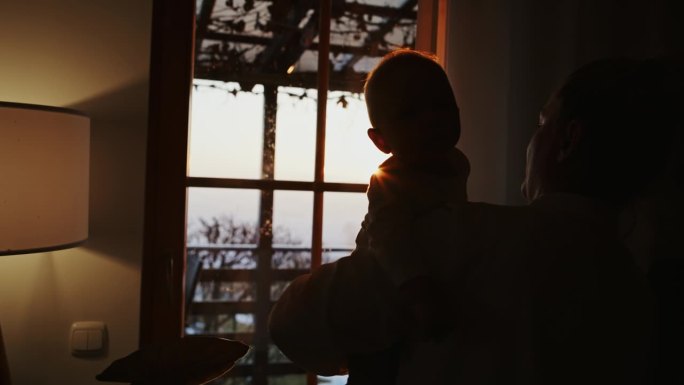 夕阳下母亲带着孩子在家的剪影
