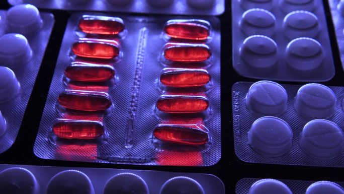红色软胶囊的水泡在白色药片的水泡之间旋转，测试新的止痛药或含有更高剂量活性物质的抗生素