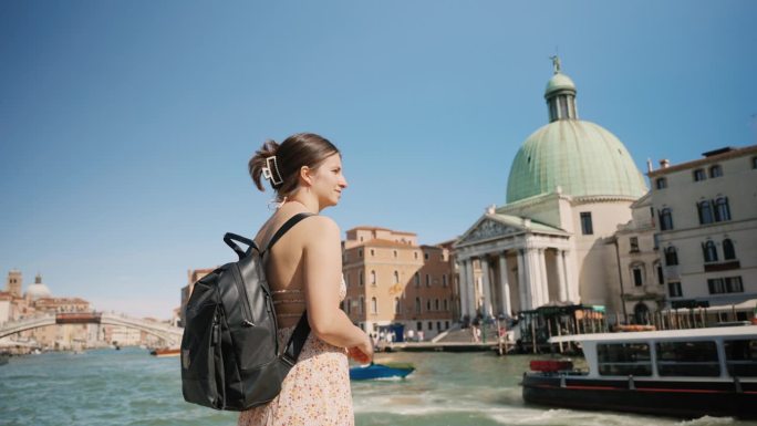 度假期间，年轻女游客背着背包站在威尼斯运河附近
