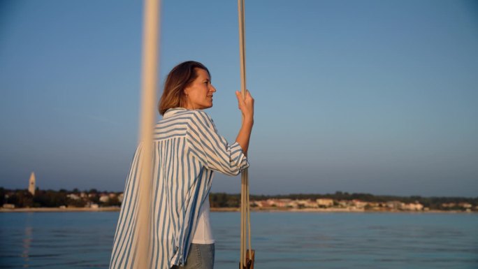 海岸奥德赛:一名女子在一艘驶向海岸美丽岛屿的船上欣赏风景