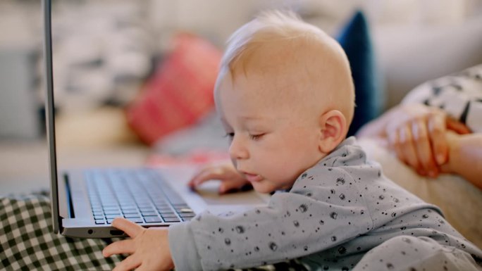 好奇的小婴儿和妈妈在家里使用笔记本电脑