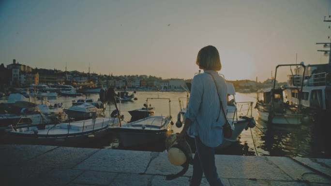 拍摄宁静:一名女子用她的手机在码头前的码头上拍摄罗维尼