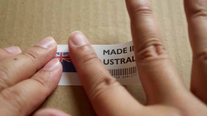 手应用在澳大利亚制造的旗帜标签上的运输箱与产品优质条码。制造和交付。产品出厂进出口。