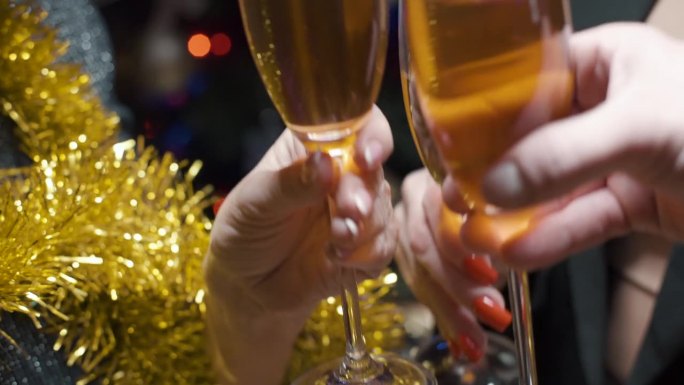 人们举着香槟酒，对着装饰着发光花环的圣诞树欢呼。背景模糊，散景