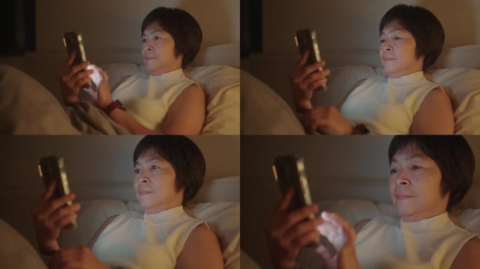 成熟的女人晚上在床上玩智能手机。