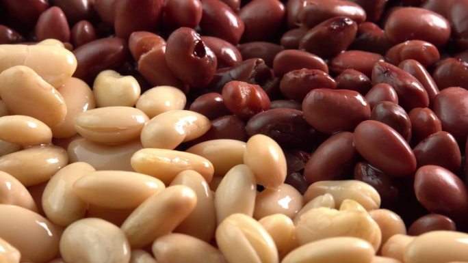 红芸豆和白芸豆罐头旋转背景近距离侧视图低光。有机蒸豆。墨西哥菜的腌豆