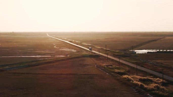 航拍跟踪一辆运输卡车，导航一条笔直的道路，朝着夕阳的光辉怀抱前进，4K60FPS，电影级