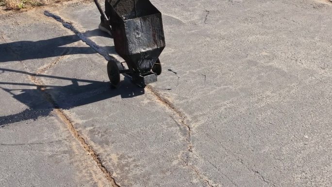 沥青修补工进行涂覆填充沥青裂缝，封堵沥青乳化路面