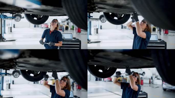 在汽车修理店汽车下面工作的女机械师