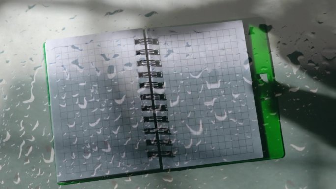 笔在记事本上的影子，投下阴影。工作场所和讲故事。透过湿漉漉的玻璃窗看到雨滴