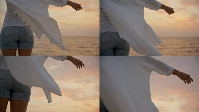 SLO MO海滨日落:女子站在码头上，张开双臂，拥抱美丽的夜空