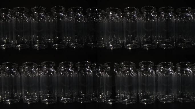 一排排用于疫苗生产和黑色背景包装的空玻璃瓶