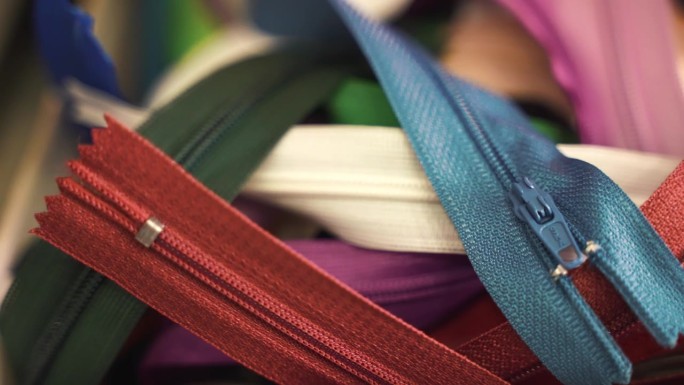 裁缝车间的彩色面料拉链，缝制和修补衣服的不同长度、形状和尺寸的拉链，裁缝工作过程中必要的材料