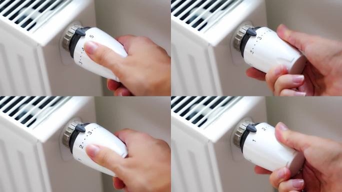一个女人的手在转动电池加热旋钮。在家里的公寓里供暖。供热价格。