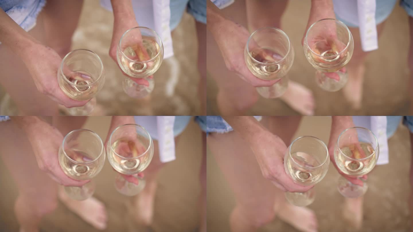 在女人腿和海浪沙滩的散焦背景下，挥舞着玻璃杯中的白葡萄酒