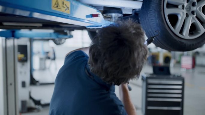 男机械师与光在修理厂检查汽车底盘