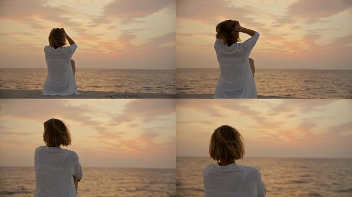 SLO MO海滨日落:一名女子在海岸码头欣赏日落