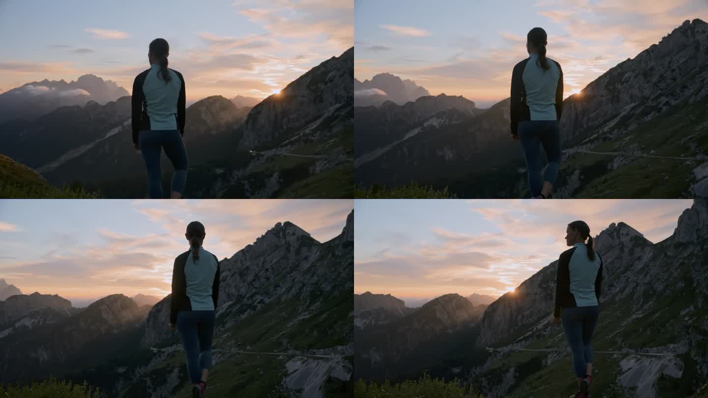 站着欣赏日出时壮丽的山脉景色的女人