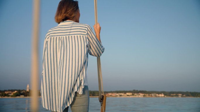 《海岸奥德赛》:一名女子站在船头，欣赏着美丽的海岸
