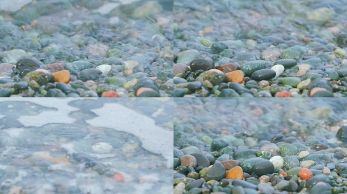 五颜六色的海卵石。小泡沫海浪在卵石滩上破碎。关闭了。