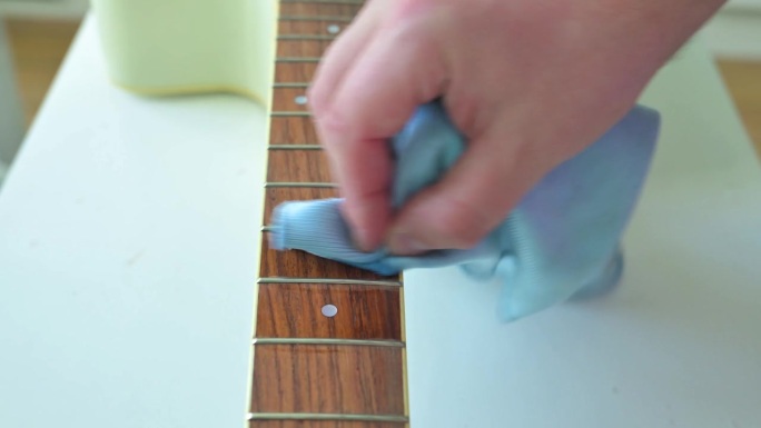 男子清洗白色原声吉他的吉他颈。吉他服务理念。4k视频片段UHD 3840x2160