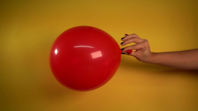 美丽的红色气球在女人的手中放气