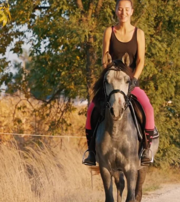 微笑的年轻牧场主在秋天的乡间小路上骑马
