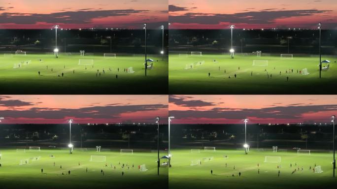 运动员们晚上在公共体育公园的照明体育场踢足球