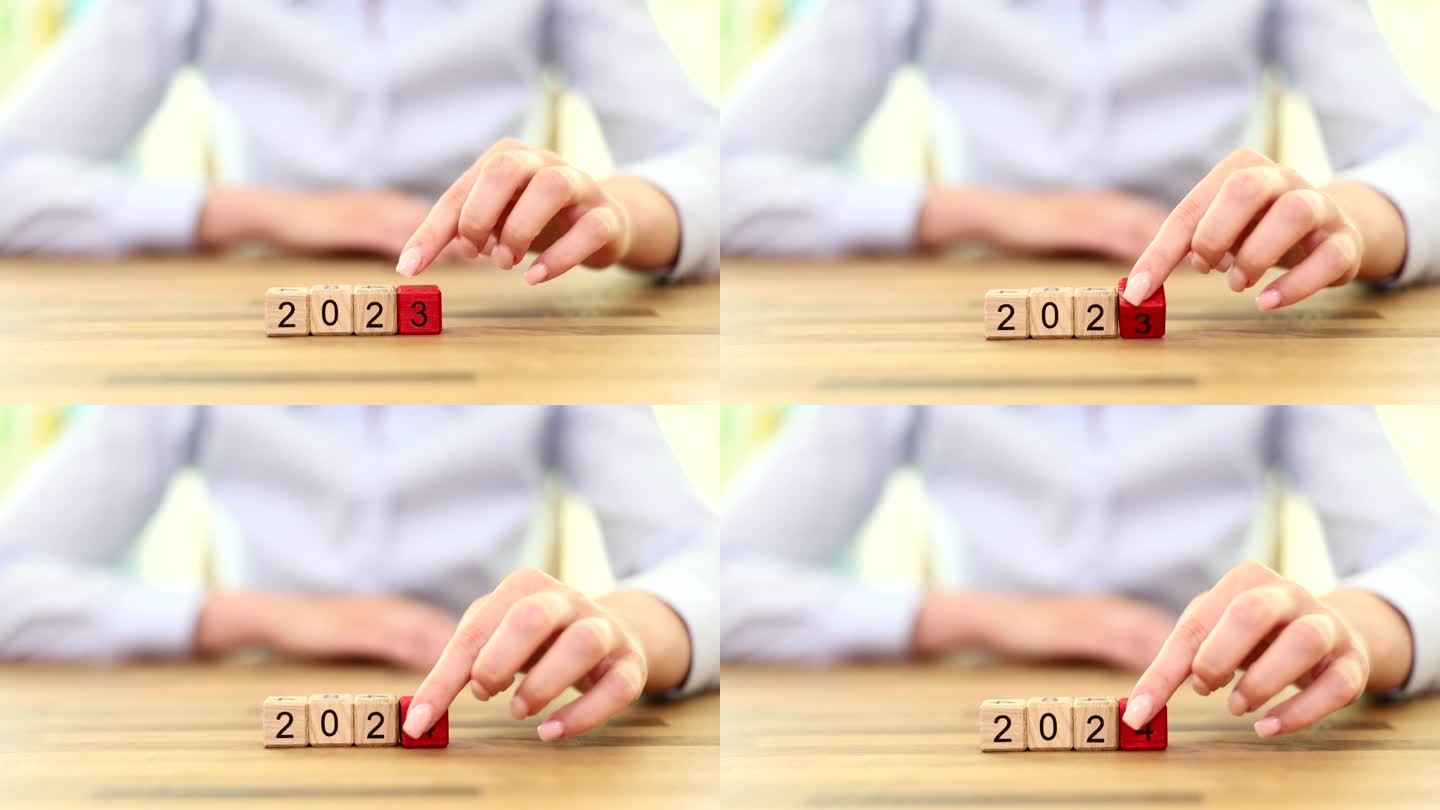从2023年到2024年，女人用手翻转木块的特写