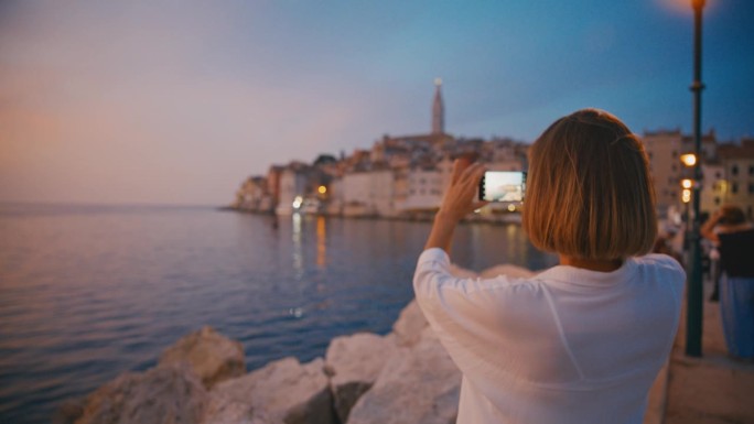 拍摄宁静:日落时分，女人用手机捕捉老城的魅力