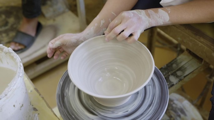 艺术家的双手熟练地在纺车上塑造粘土。