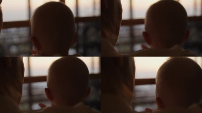 夕阳下，母亲带着婴儿望向窗外