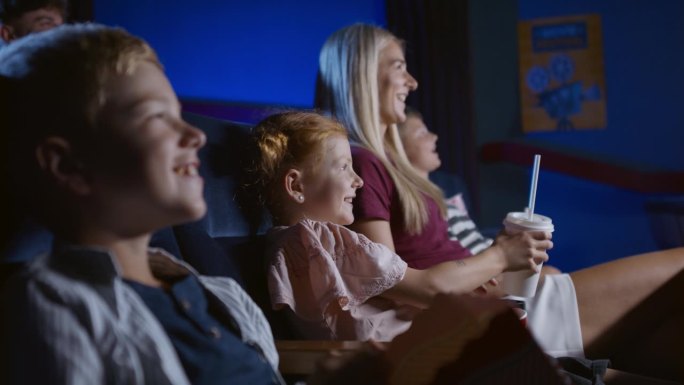 妈妈带着开心的小孩子在电影院，看电影。