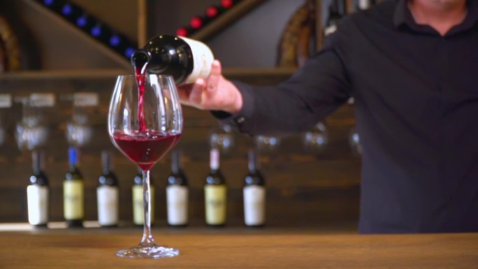 红酒被漂亮地倒入玻璃杯中。酒保把红酒倒进杯子里。葡萄酒的生产和销售。