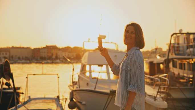 拍摄宁静:女人微笑着用手机拍摄码头上的日出