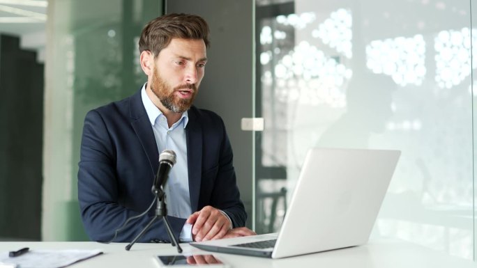 自信的导师，穿着正装，坐在办公室用笔记本电脑和麦克风进行视频通话。