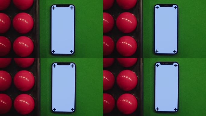 色度键手机在绿色台球桌的红色球之间。台球比赛。绿屏智能手机