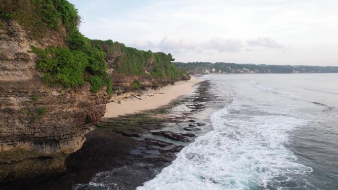 陡峭的海岸岩石，海浪在粗糙的海滩上破碎成白水，航拍