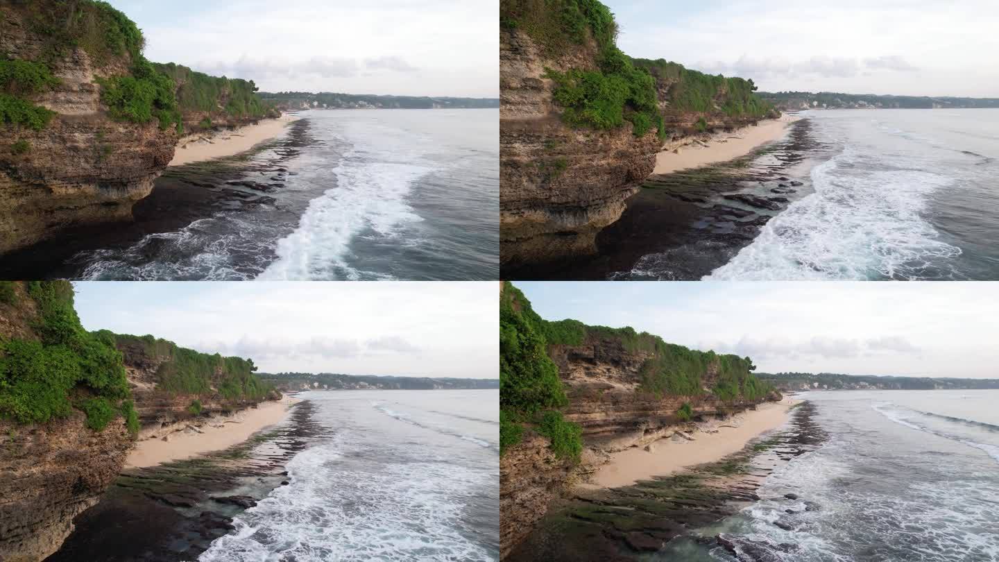 陡峭的海岸岩石，海浪在粗糙的海滩上破碎成白水，航拍
