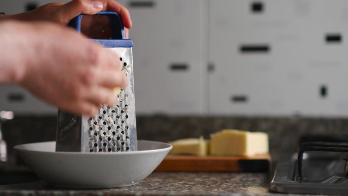 两只手用食物刮刀碾碎落在砧板附近白色盘子上的马苏里拉奶酪，水平视频