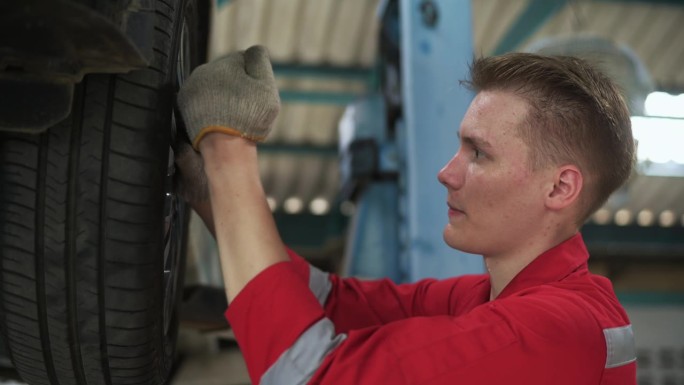 年轻的白人修理工在汽车修理厂分析和修理坏了的汽车